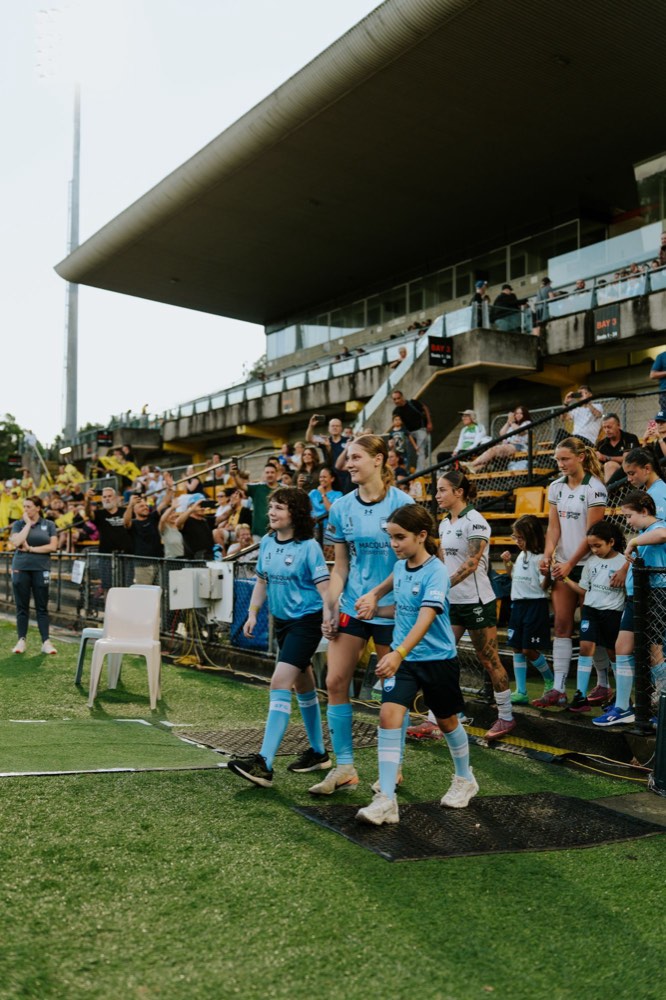Sydney FC players walking out onto the pitch hand in hand with young mascots